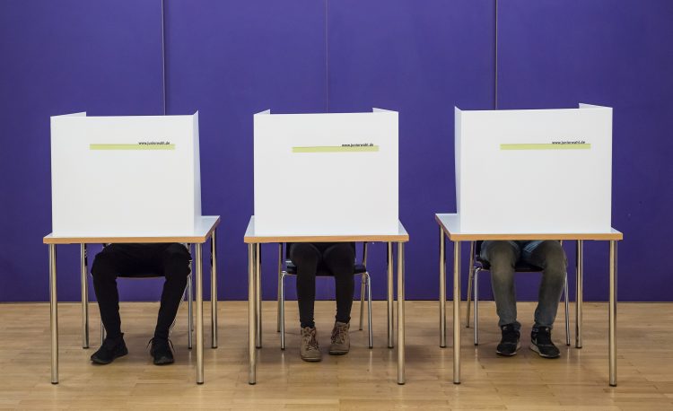 Drei Wahlkabinen mit Wählern Pressefoto Juniorwahl